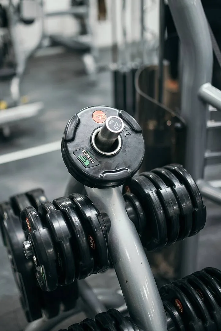 Rak dumbel di area latihan Jambi Bugar Gym, tanpa orang